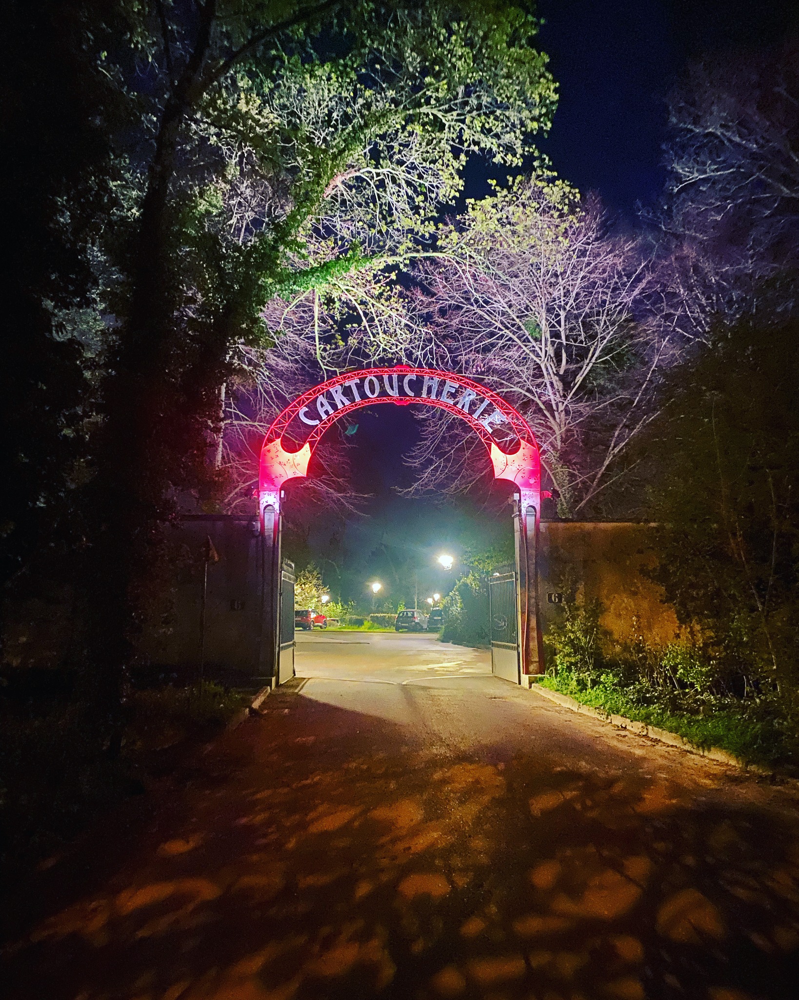 L’ingresso della Cartoucherie illuminato di notte, tra gli alberi