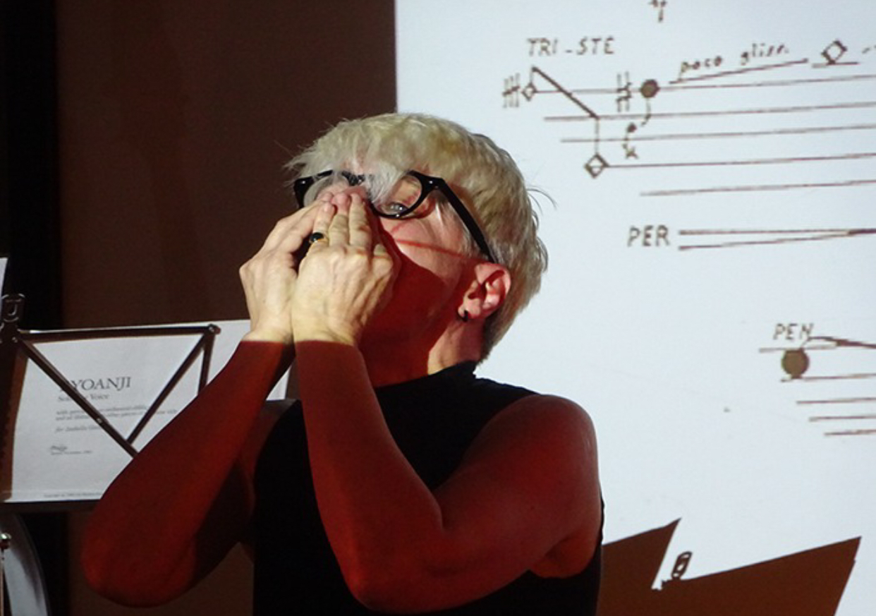 Francesca Della Monica con le mani davanti alla bocca, davanti a una partitura proiettata