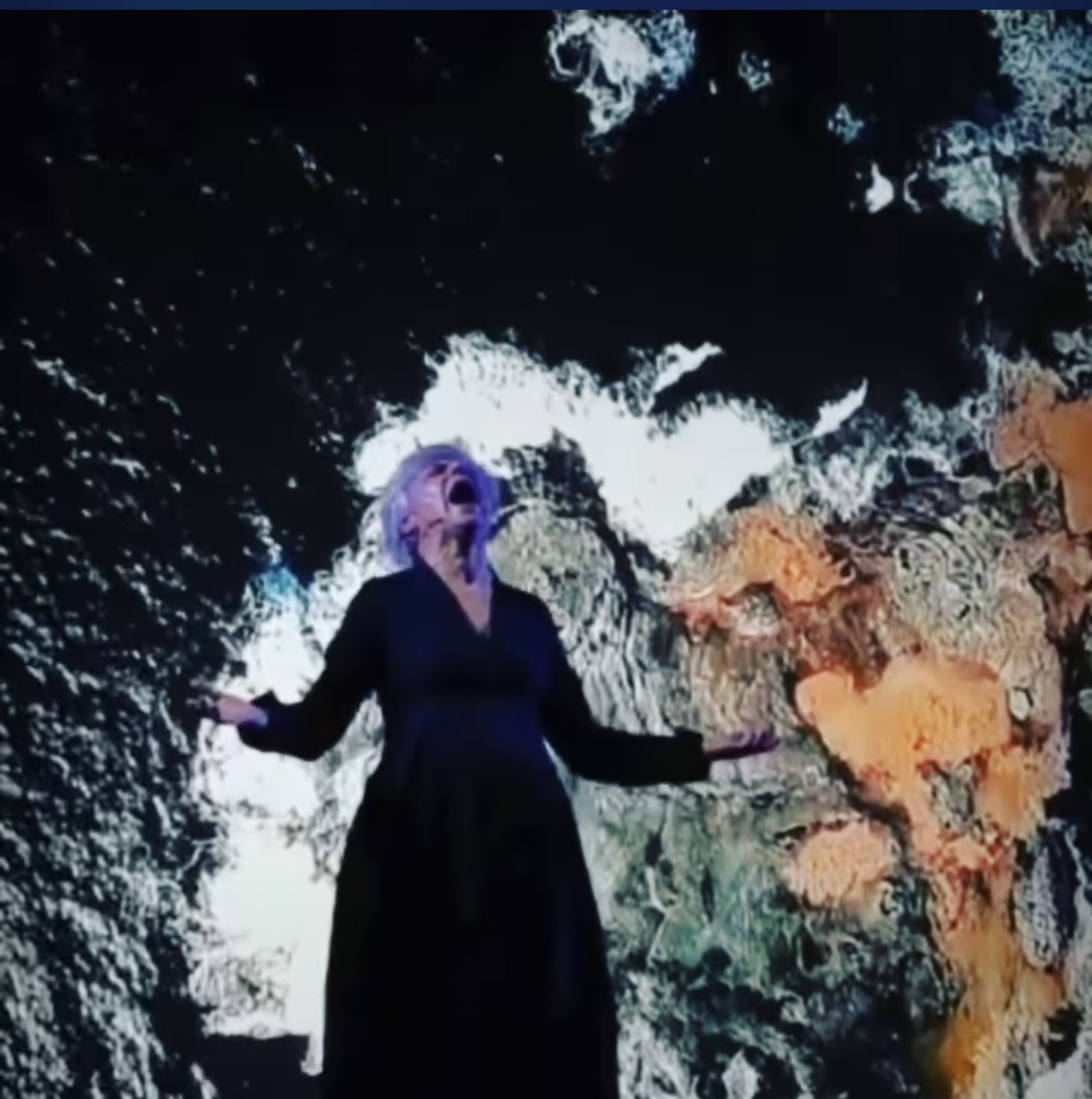 Francesca Della Monica durante una performance, davanti a proiezioni luminose
